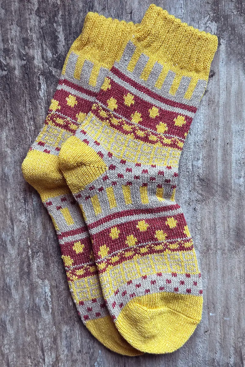 Nordic Style Socks in Mustard Cross by Mabel + Meg on wood background